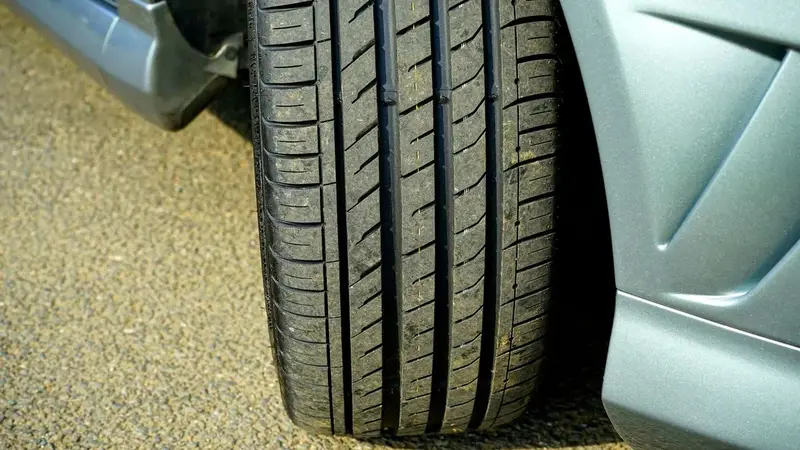 Car tire on asphalt showing tread pattern for checking uneven wear