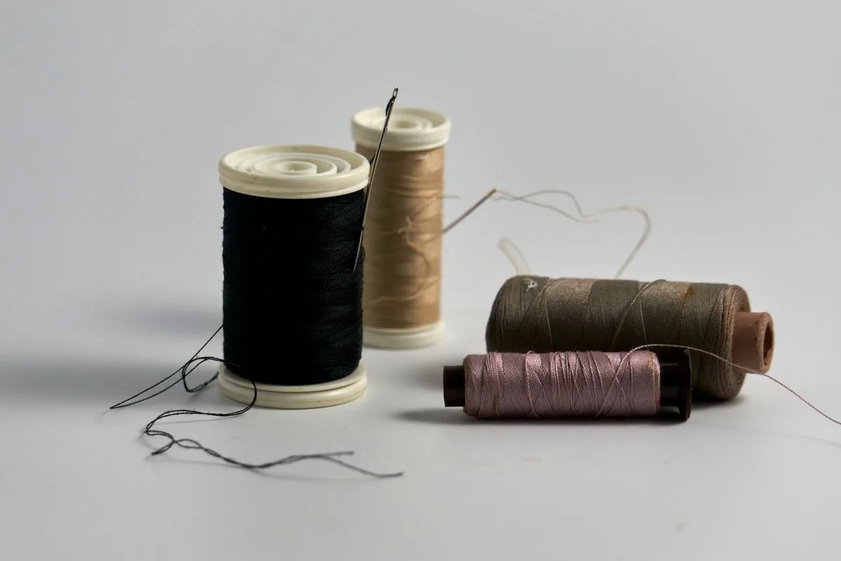 How to sew a button starting with needles and thread close-up