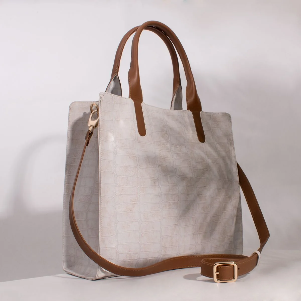 Beige leather handbag with brown straps photographed in a studio