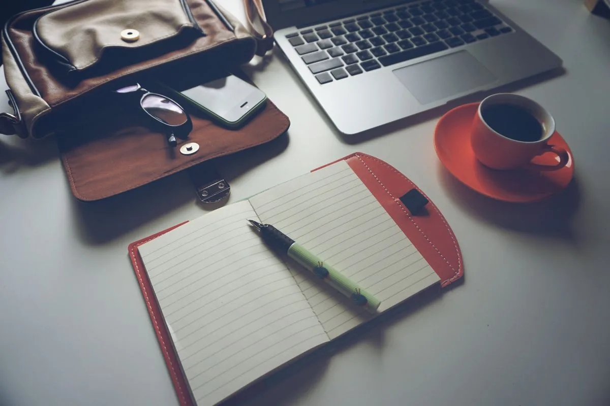 Tidy office workspace with laptop, notebook, pen and coffee