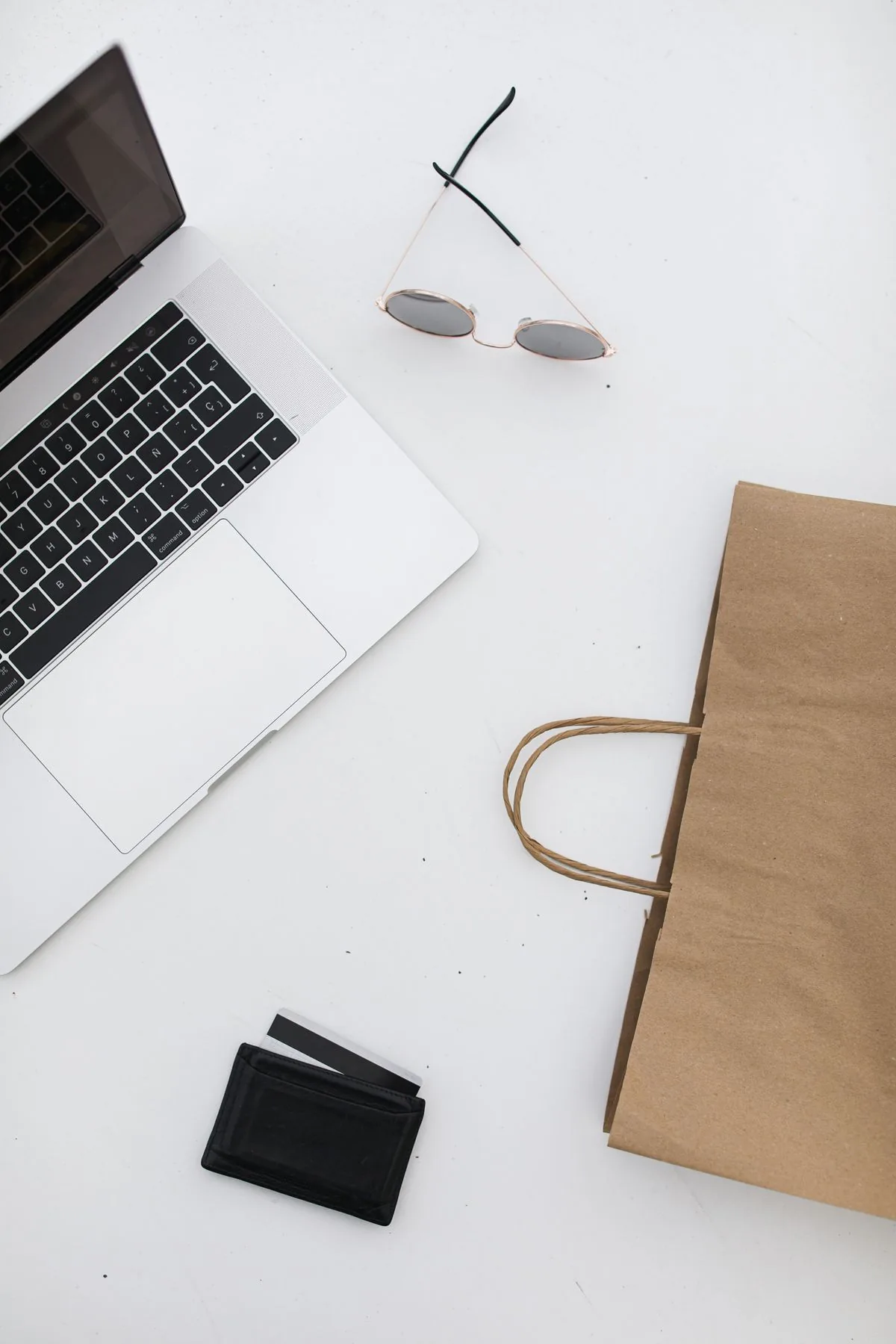 Top-down view of a minimalist desk with laptop, sunglasses and wallet