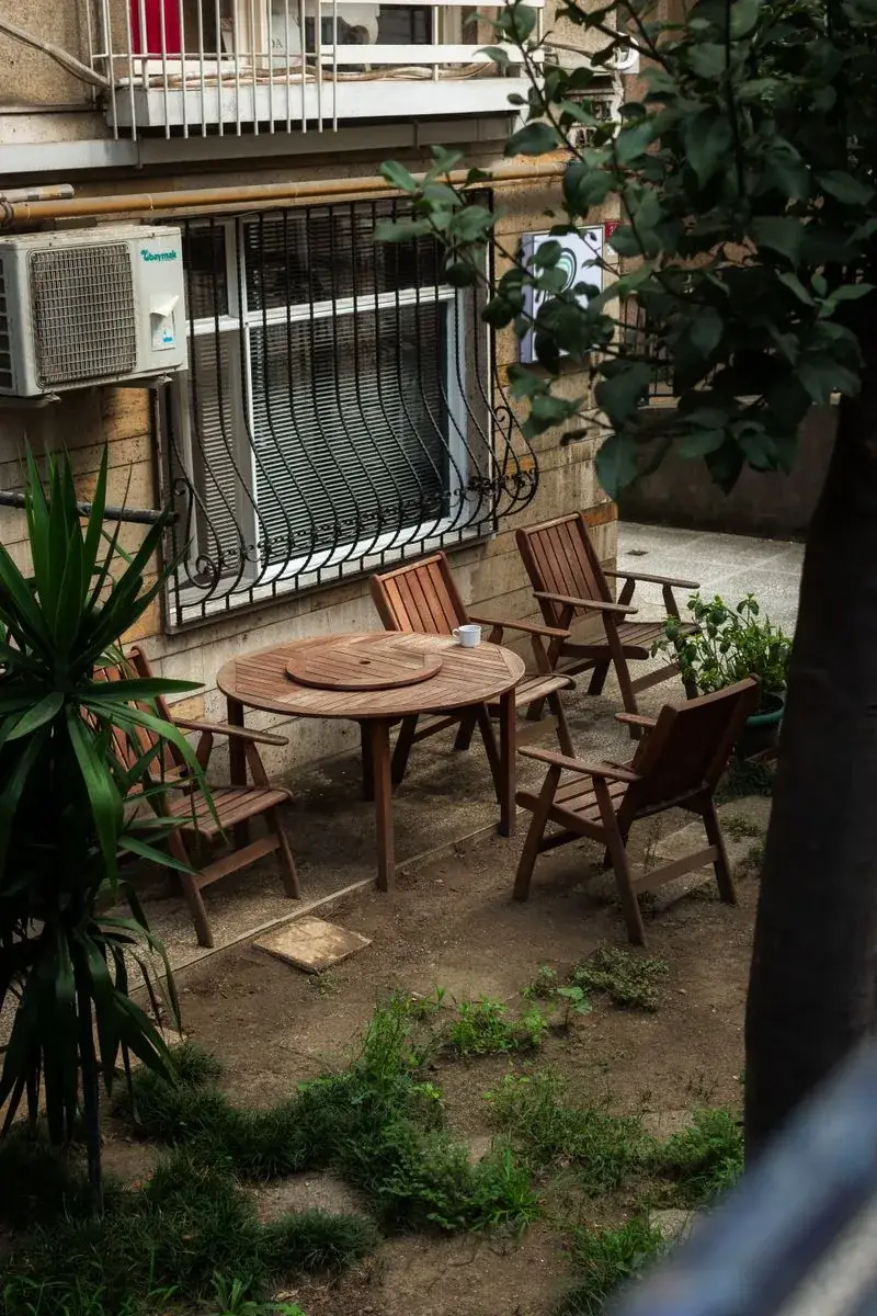 Wooden patio chairs and round table with greenery staged where to sell outdoor furniture photos