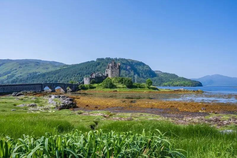 Eilean Donan Castle on a calm loch where to travel in summer for cool northern escapes